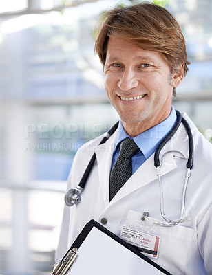 Buy stock photo A handsome doctor smiling at the camera while holding a clipboard