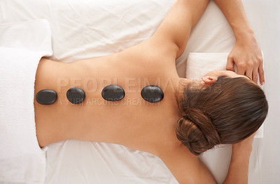 Buy stock photo Hot stone, massage and top view of woman in salon to relax for skincare, beauty or pamper body for wellness at luxury spa. Therapy, above and person with rocks in treatment for back, spine and health
