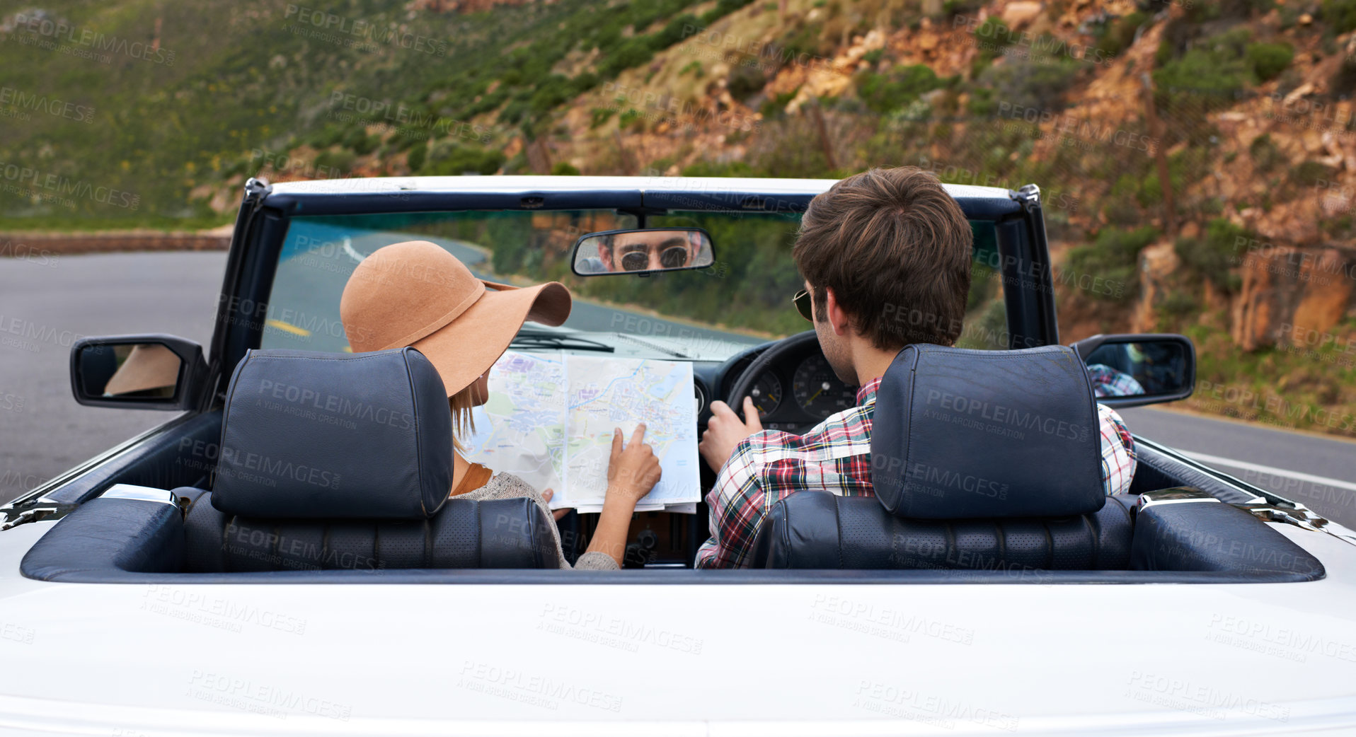 Buy stock photo Rearview shot of a young couple reading a map while sitting in a car