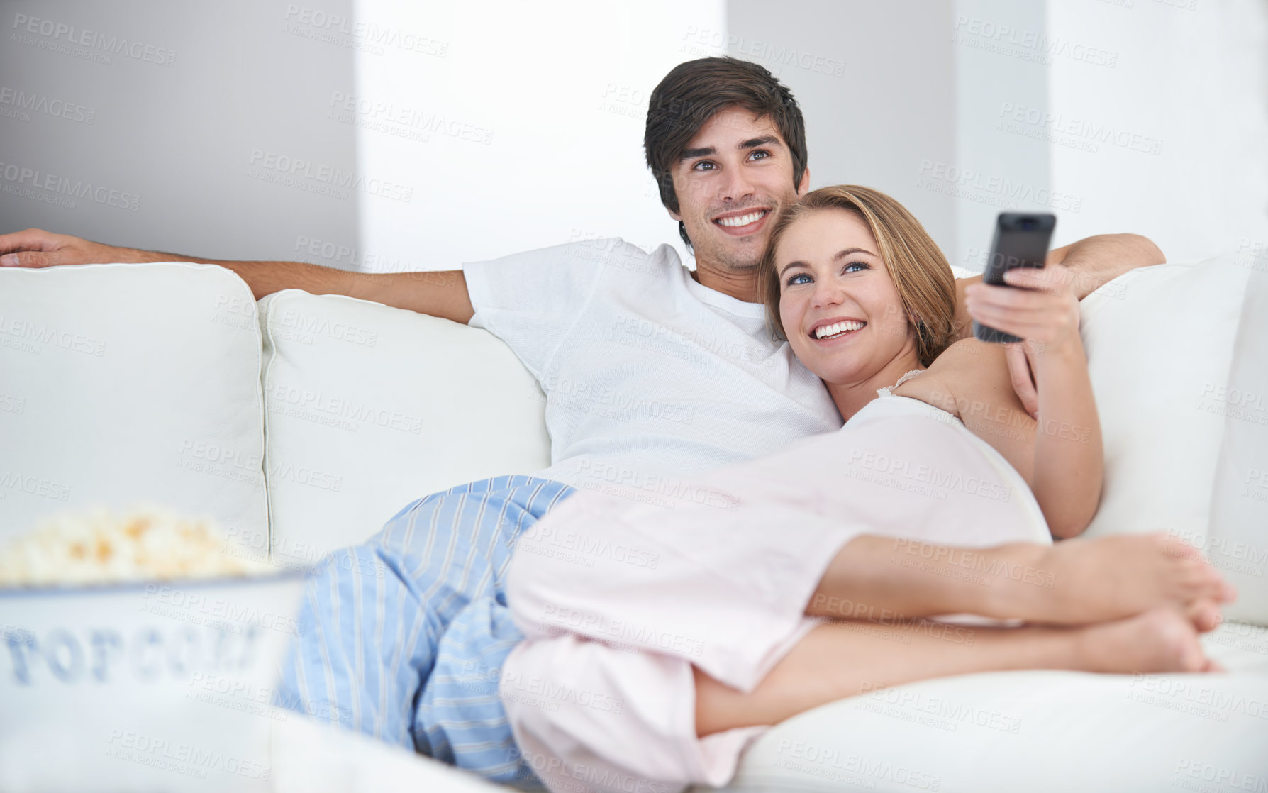 Buy stock photo A young couple watching a movie at home