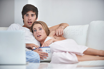 Buy stock photo Shot of a young couple watching a scary movie at home