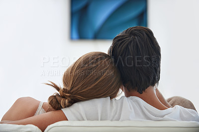 Buy stock photo Back, relax and a couple watching tv on the sofa with affection, comfort and content at home. Calm, love and a man and woman sitting on the living room couch for a movie, film or show on television