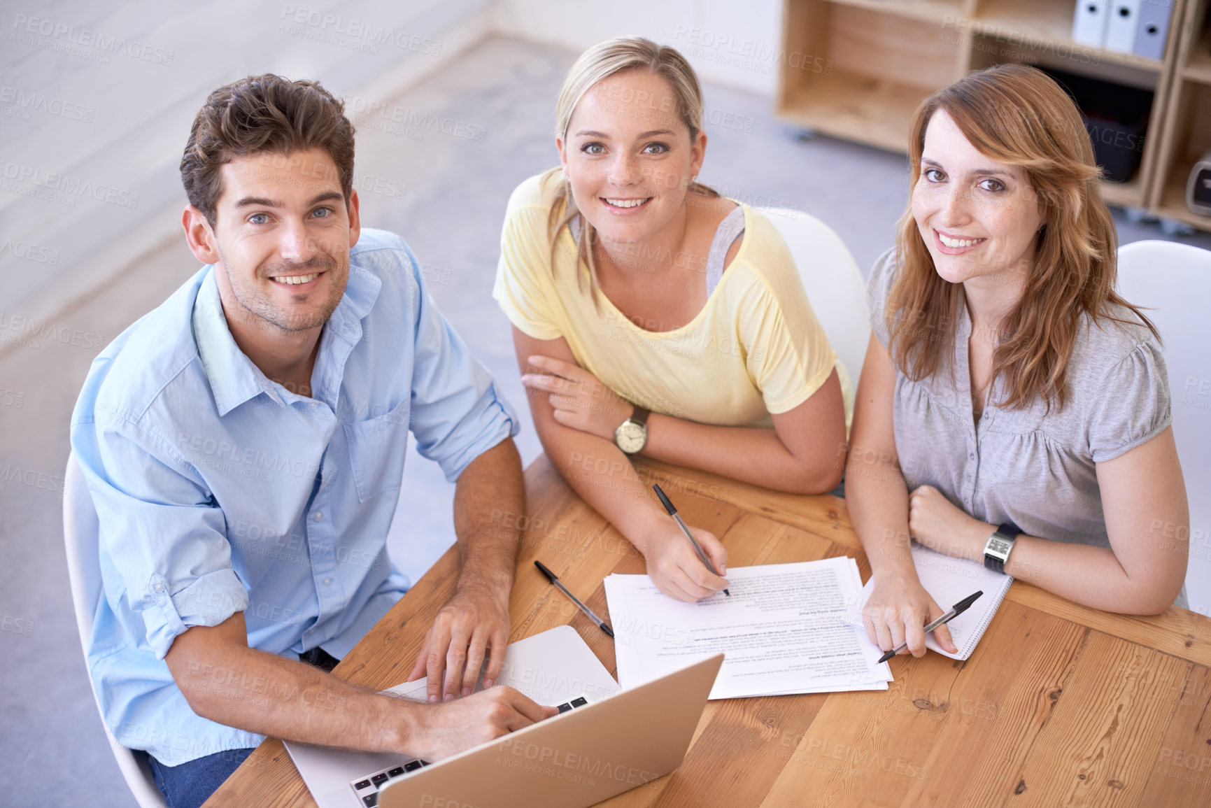 Buy stock photo High angle shot of three young businesspeople sitting at a table