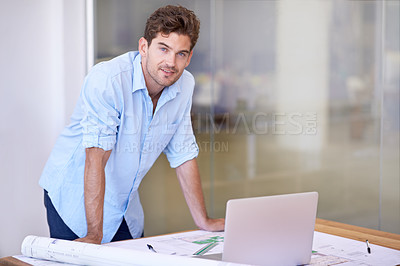 Buy stock photo Shot of a young designer at work with some blueprints and a laptop