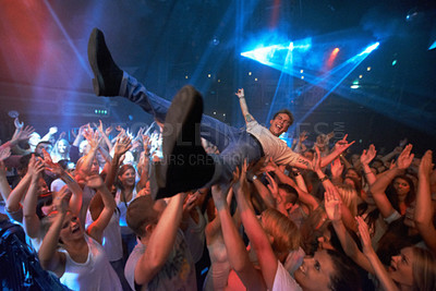 Buy stock photo Concert, party and man crowd surfing in nightclub with fans in disco, dance and rave celebration. Freedom, energy and band musician jump in audience after live performance, musical event and festival