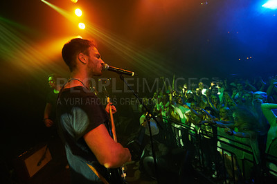 Buy stock photo Concert, band and music with a man guitarist playing at a gig for a crowd or audience at a performance event. Festival, stage and social with a male artist strumming a guitar while singing at a show