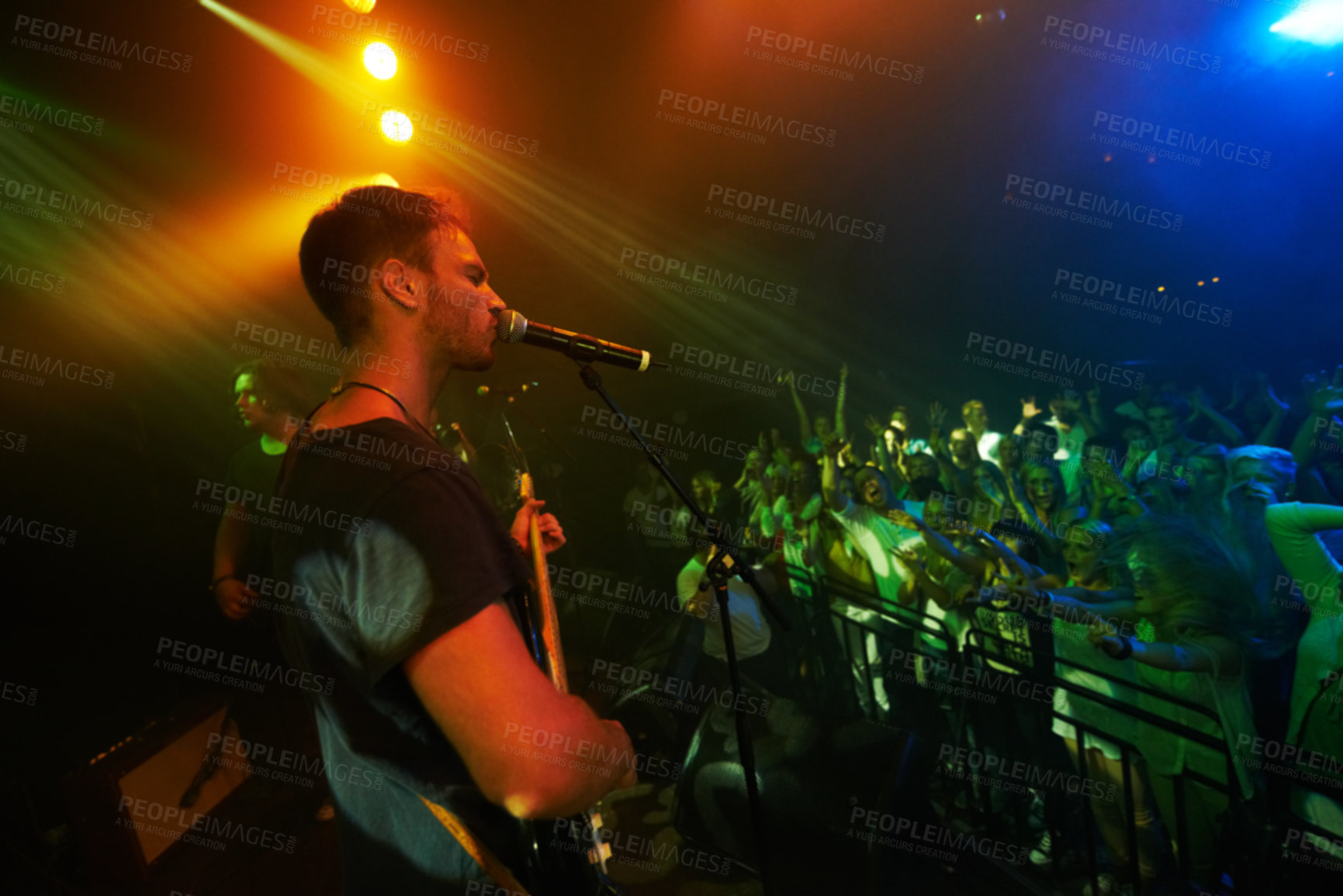 Buy stock photo Concert, band and music with a man guitarist playing at a gig for a crowd or audience at a performance event. Festival, stage and social with a male artist strumming a guitar while singing at a show