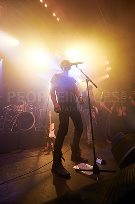 Buy stock photo Music, rock and stage with man and microphone singing for concert, festival and party event. Light, celebration and performance with singer and band at nightclub for disco, techno or new year show