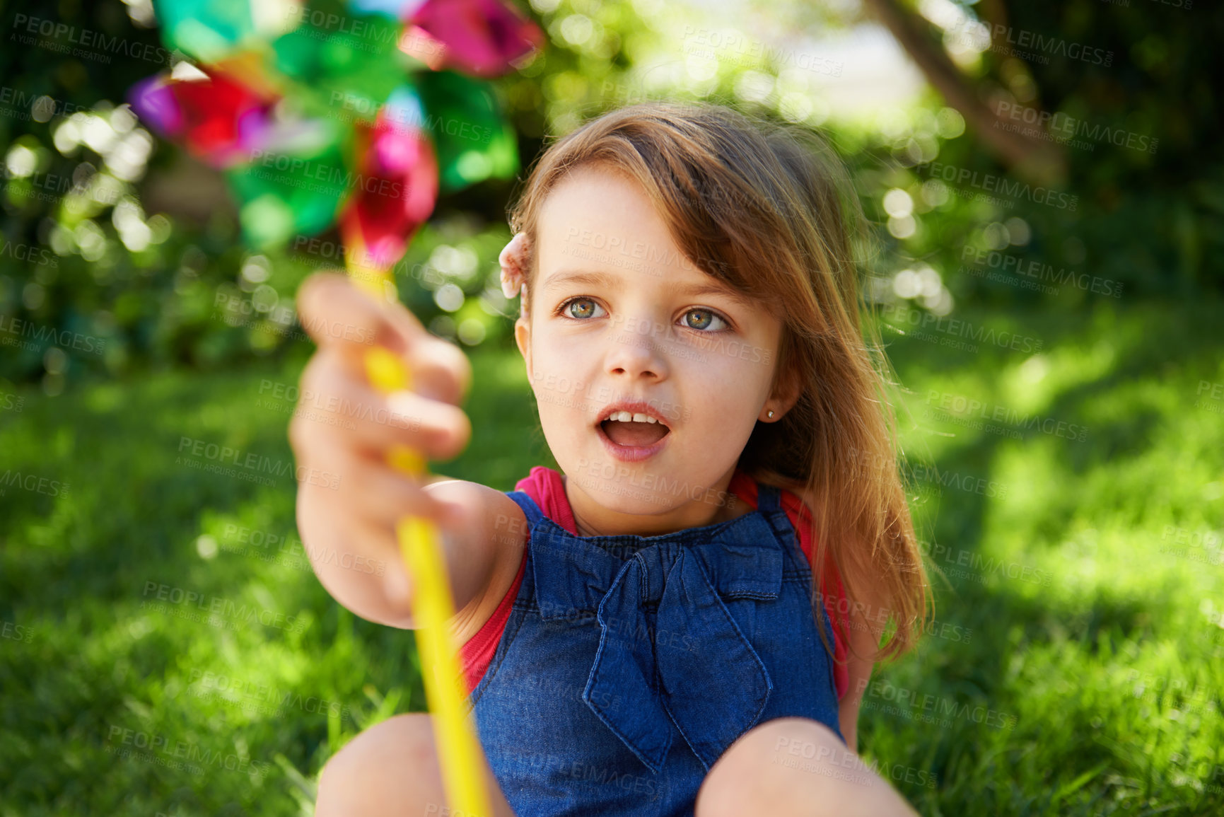 Buy stock photo Toy, girl and child playing with windmill on grass in nature, relax and having fun on lawn outdoor. Park, garden and young kid with pinwheel on summer vacation closeup for recreation, game or leisure