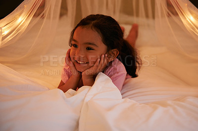 Buy stock photo Shot of a cute little girl lying on her stomach on a bed