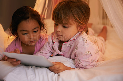 Buy stock photo Shot of two cute little girls reading a story together