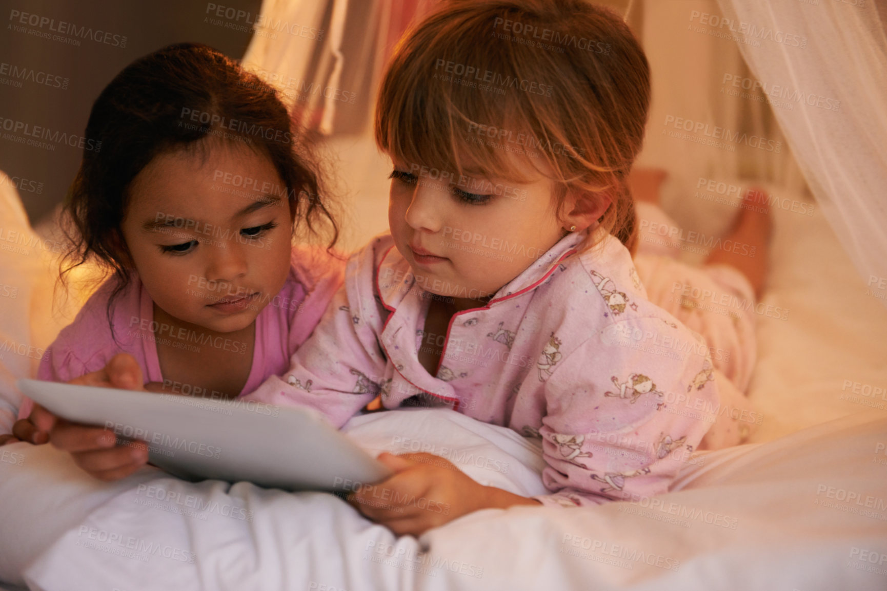 Buy stock photo Shot of two cute little girls reading a story together