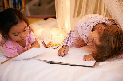 Buy stock photo Kids, color pencil and drawing on bed for sleepover, creative and relax in bedroom for weekend. Young girls, playing and learning art in book at night, friends and bonding by fairy light in pyjamas