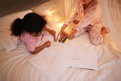 Buy stock photo Girls, color pencil and drawing on bed for sleepover, creative and relax in bedroom for weekend. Young kids, playing or educational toys at night in pajamas, friends or bonding by fairy light in home