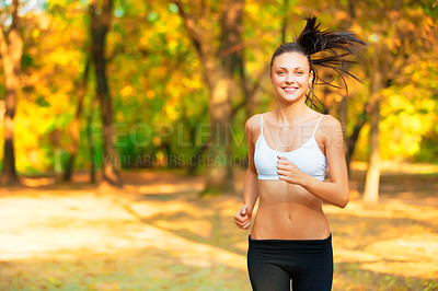 Buy stock photo Shot of a positive-looking young woman jogging in a park in autumn