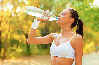 Buy stock photo Shot of a woman taking a drink of water while out for a jog in the park