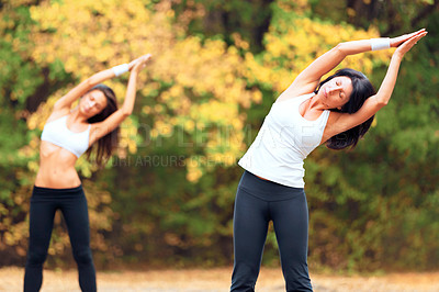 Buy stock photo Shot of two women exercising together in a park