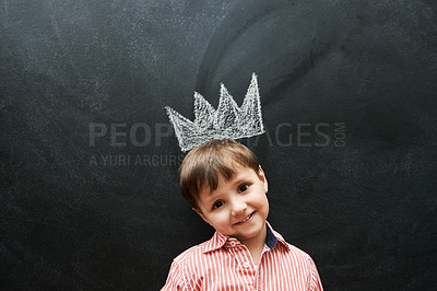 Buy stock photo Little boy, portrait and crown on chalkboard in black background and smile for school in elementary class. Kid, happiness and education for development of learner, blackboard and cute drawing