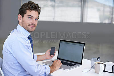 Buy stock photo Portrait of a young businessman seated at his desk with a mobile phone in his hand
