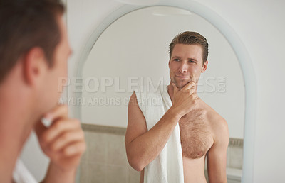 Buy stock photo A young man looking at his reflection in the mirror after a shave