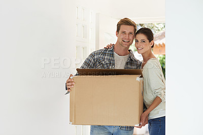 Buy stock photo Shot of a young couple carrying a box into their new home together