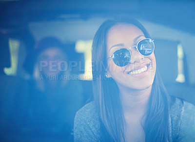 Buy stock photo A young woman wearing sunglasses sitting in the front seat of a car with her friend in the backseat