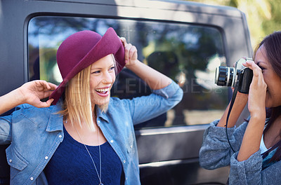 Buy stock photo Camera, photography and friends on road trip with journey, travel and creative hobby or photoshoot of model posing. Young people, women or photographer shooting by car for outdoor fashion and hat