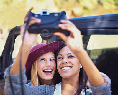 Buy stock photo Shot of a two girlfriends taking self-portraits while on a roadtrip
