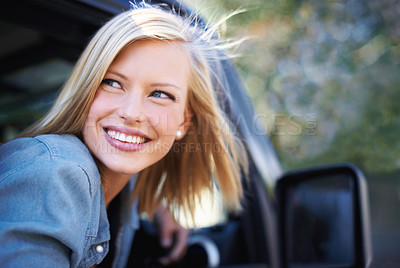 Buy stock photo A young woman feeling the breeze in her hair through an open car window