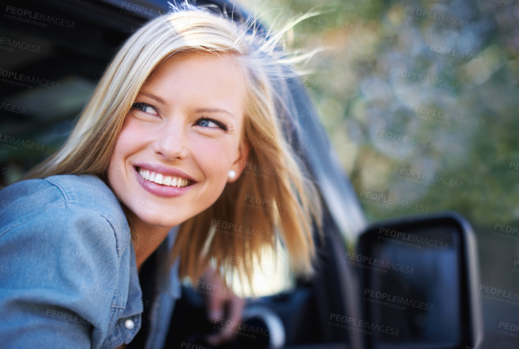 Buy stock photo A young woman feeling the breeze in her hair through an open car window