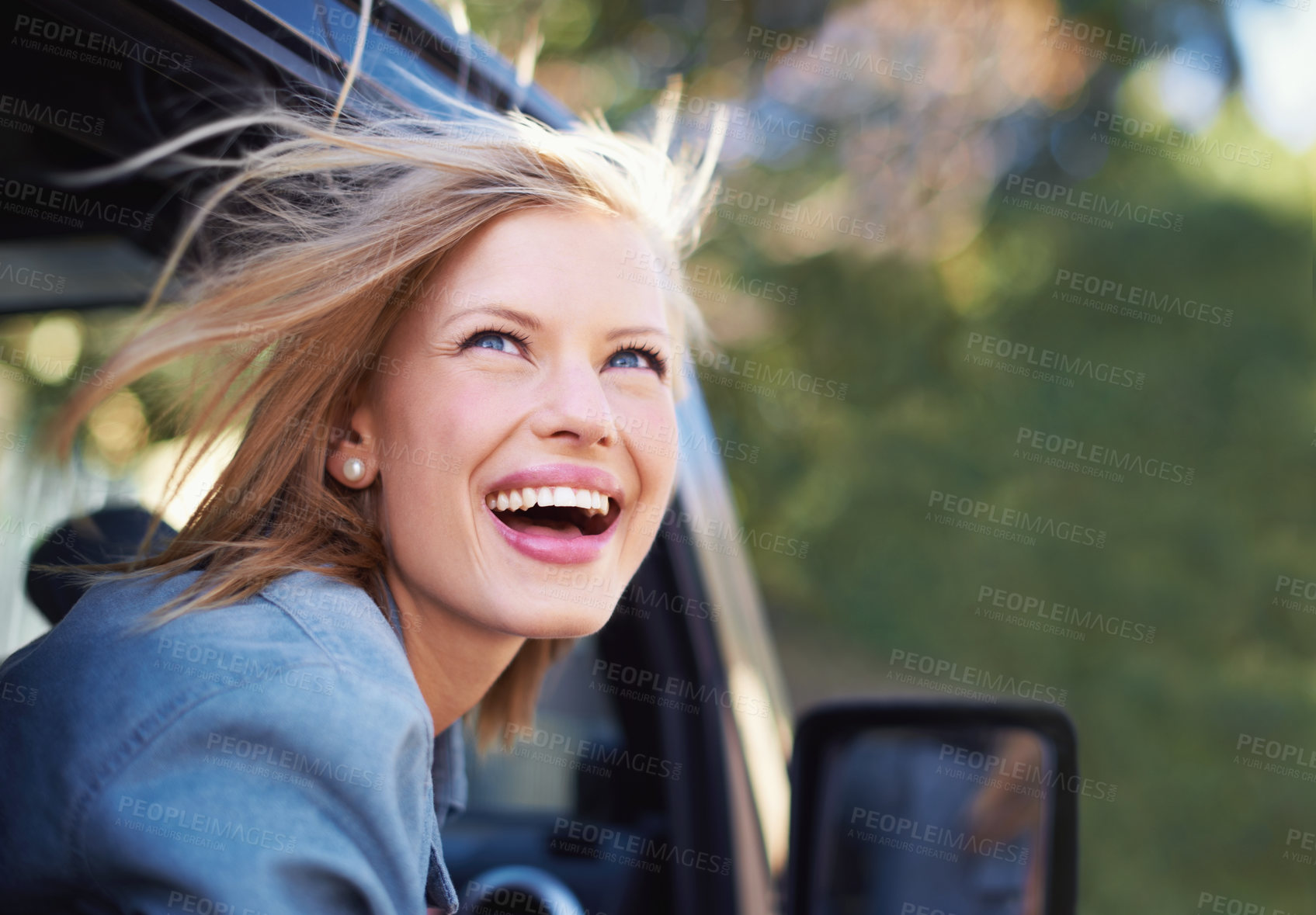 Buy stock photo A young woman feeling the breeze in her hair through an open car window