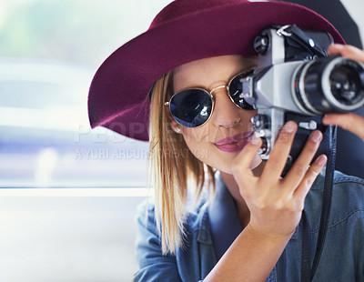 Buy stock photo A young woman wearing a hat and sunglasses taking pictures from a car