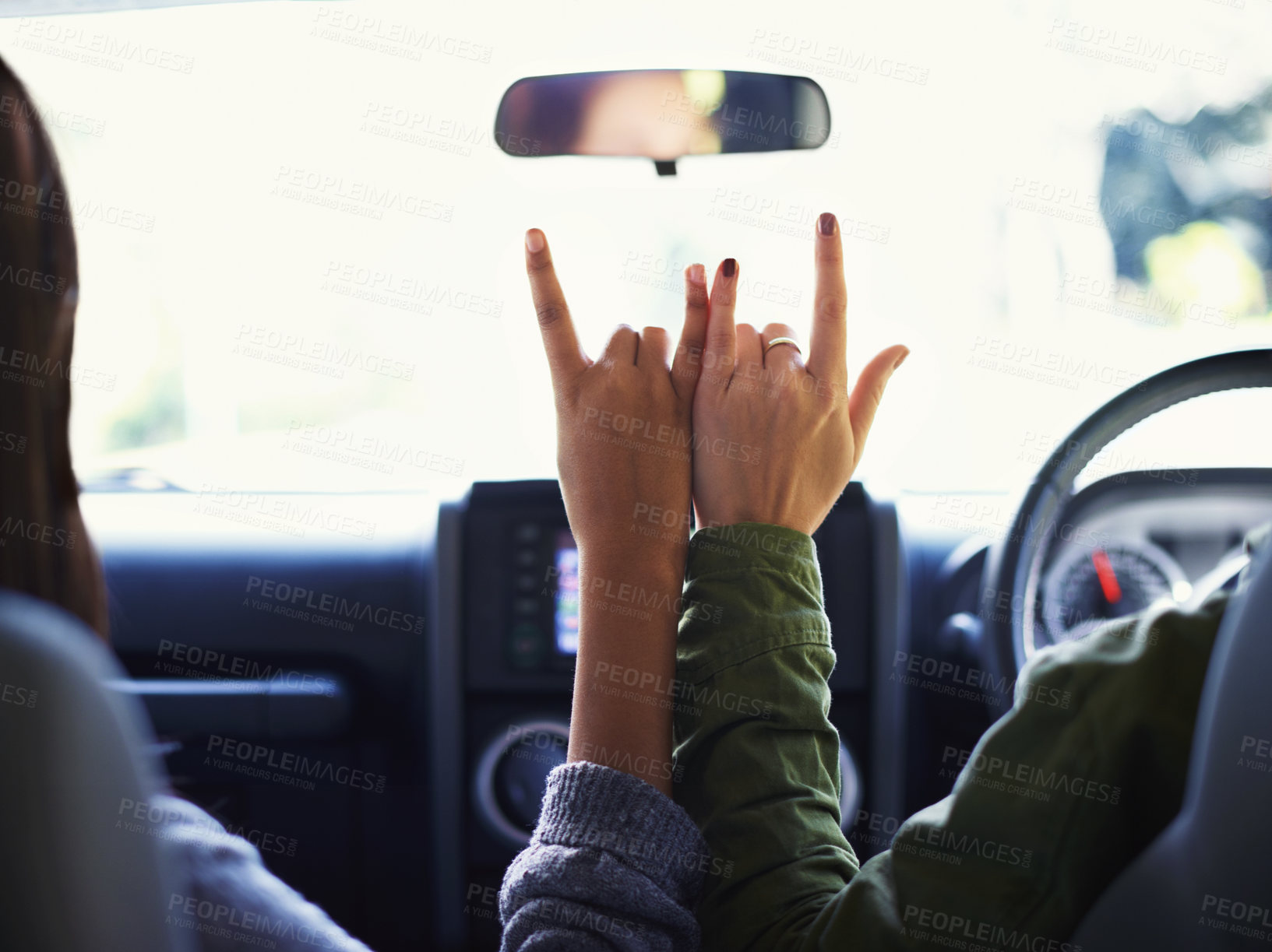 Buy stock photo Cropped view of two young women on a road trip making the "rock on"sign