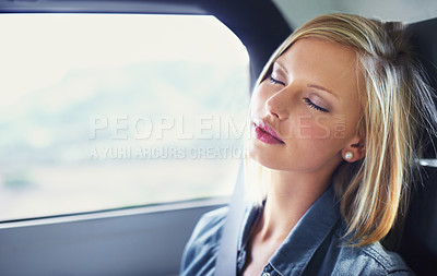 Buy stock photo Shot of an attractive young woman asleep in the backseat of a car while on a roadtrip
