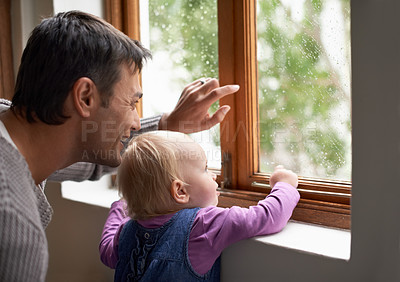 Buy stock photo A young father and his baby girl looking at something beyond the window