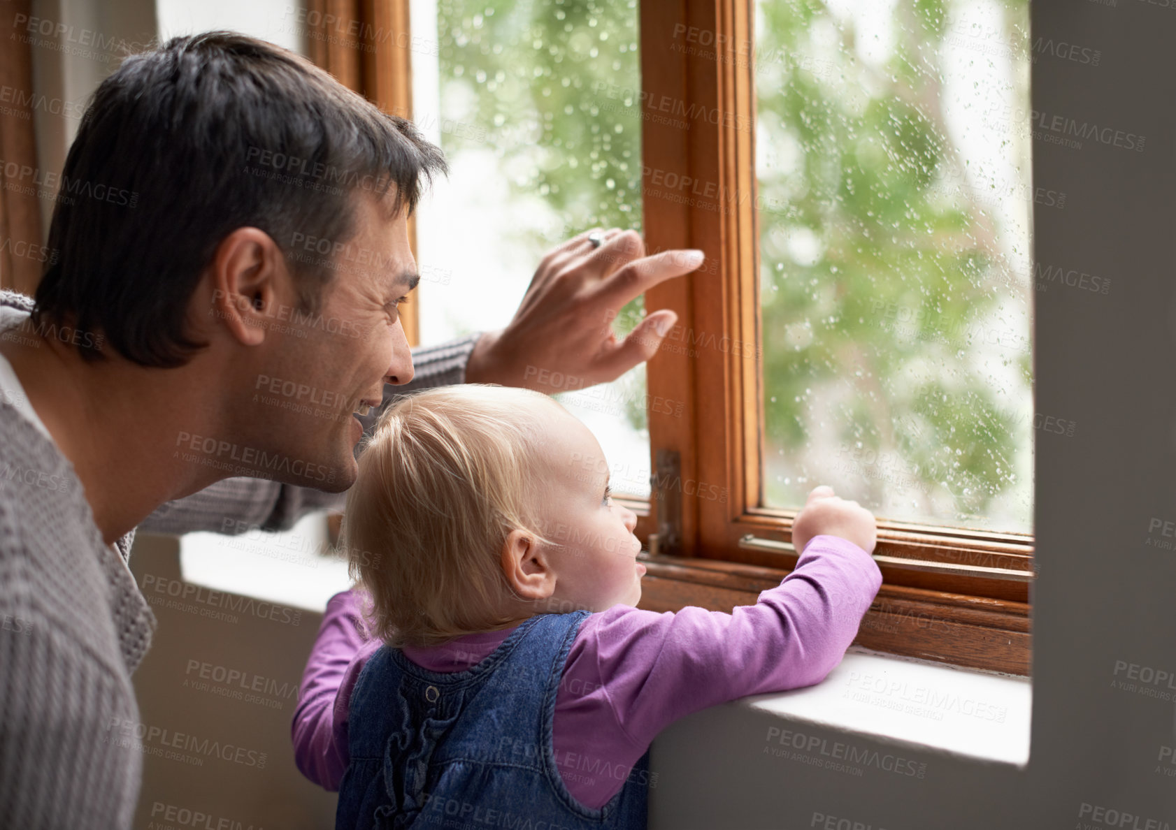 Buy stock photo A young father and his baby girl looking at something beyond the window
