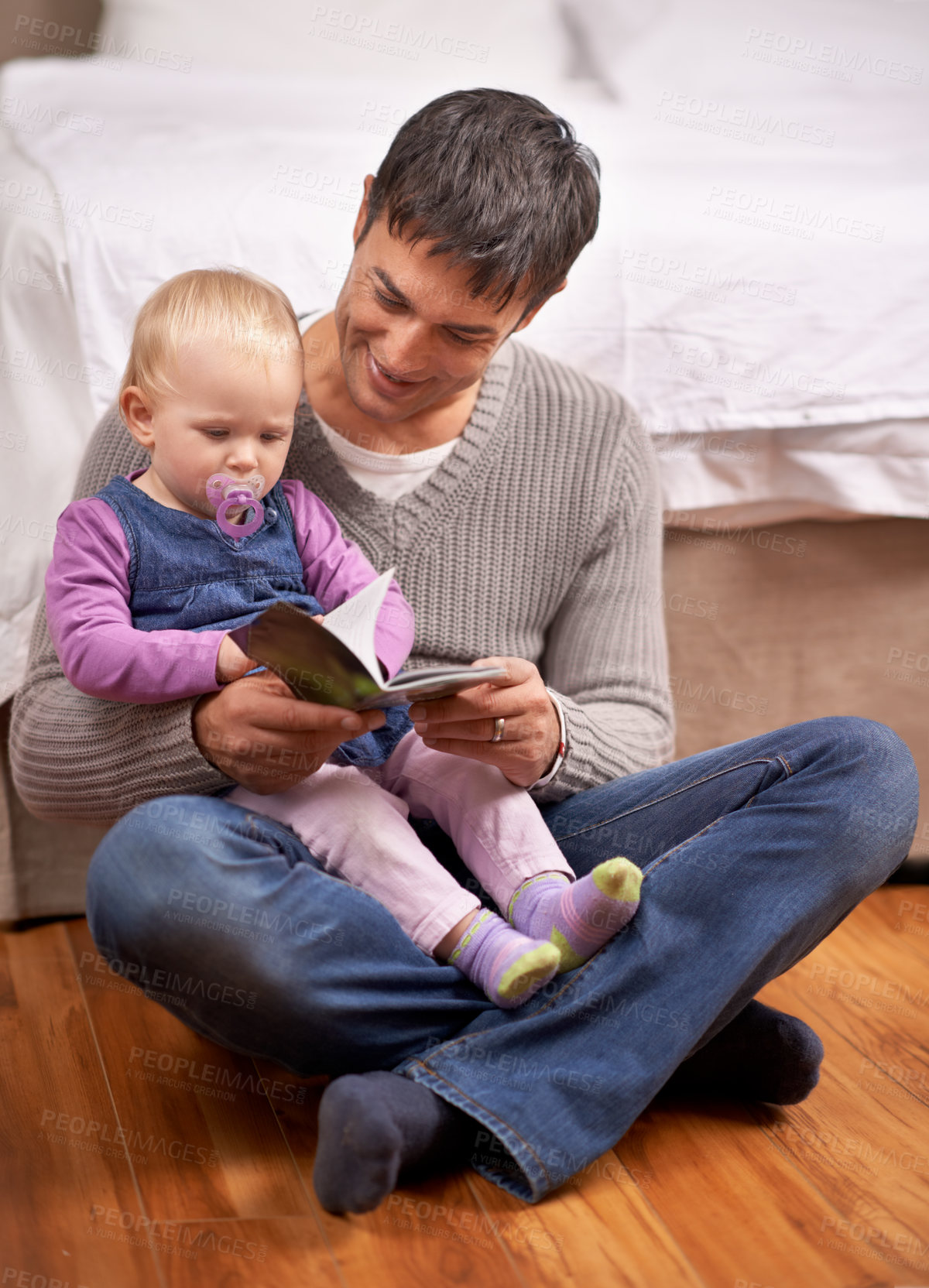Buy stock photo A young father reading his baby girl a storybook