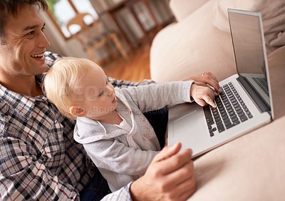 Buy stock photo A young father showing his baby girl how to use a laptop