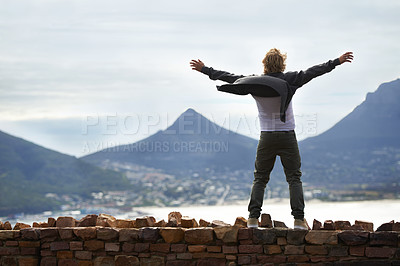 Buy stock photo Shot of a young man standing on a wall looking at the natural scenery