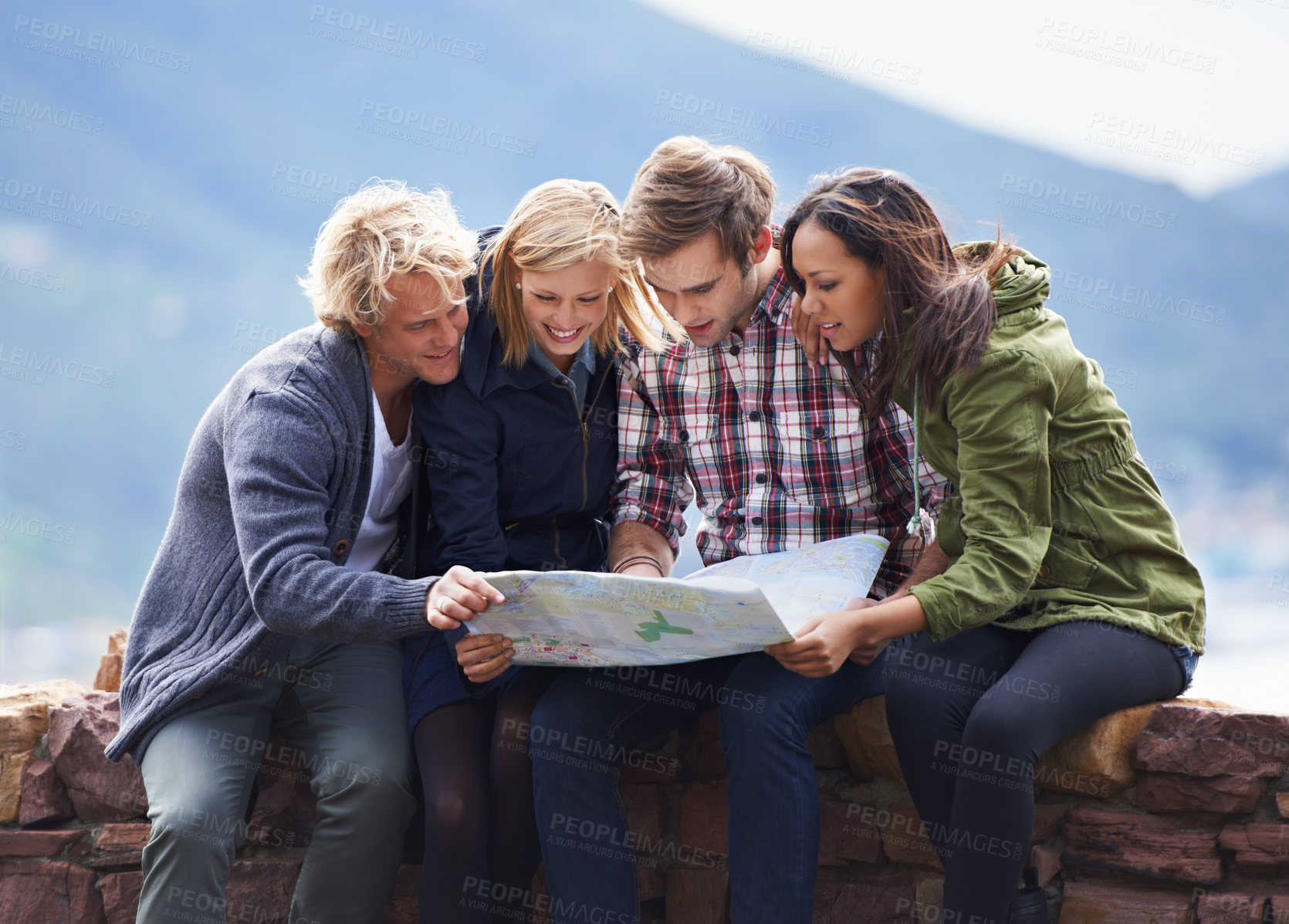 Buy stock photo Happy people, friends and map on stone wall for direction, location or planning next destination. Young group looking or checking route, path or spot for holiday weekend or outdoor vacation in nature