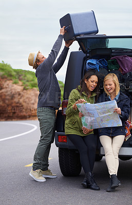 Buy stock photo Happy woman, friends and map with a car full of luggage for road trip, destination or planning outdoor vacation. Group of young people checking travel guide and packing bags for adventure or journey