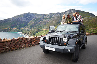 Buy stock photo Shot of a group of friends relaxing on the roof of their truck with a mountainous background