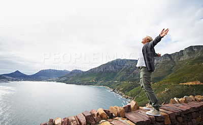 Buy stock photo Shot of a young man standing on a wall looking at the natural scenery