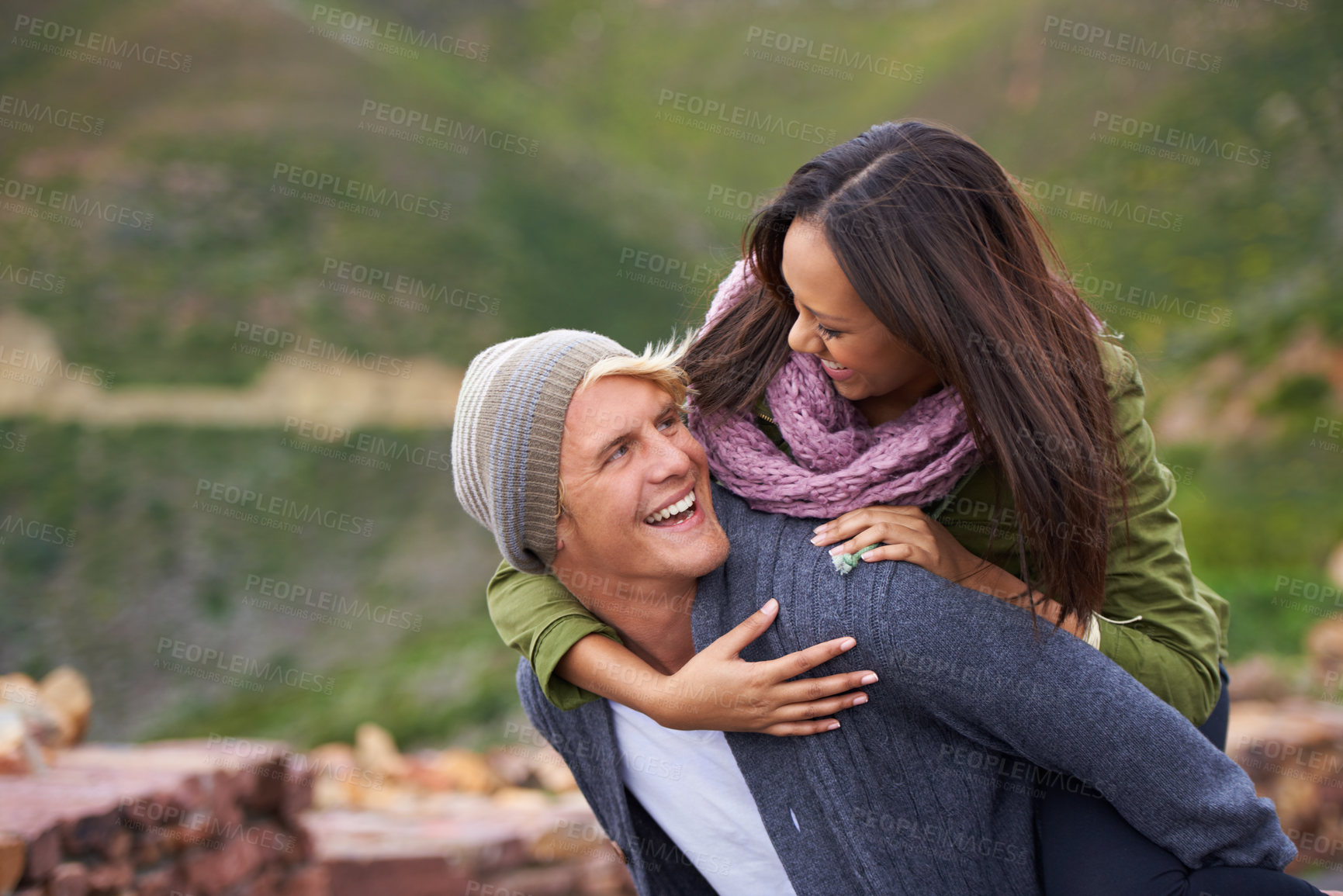 Buy stock photo Happy, couple and piggyback in nature, hiking and travel together on adventure for date on holiday. Funny, outdoor and man carrying woman, trekking and interracial people laughing in the countryside