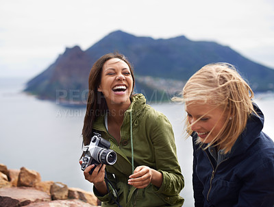 Buy stock photo A shot of two young women laughing on the side of the road during their trip