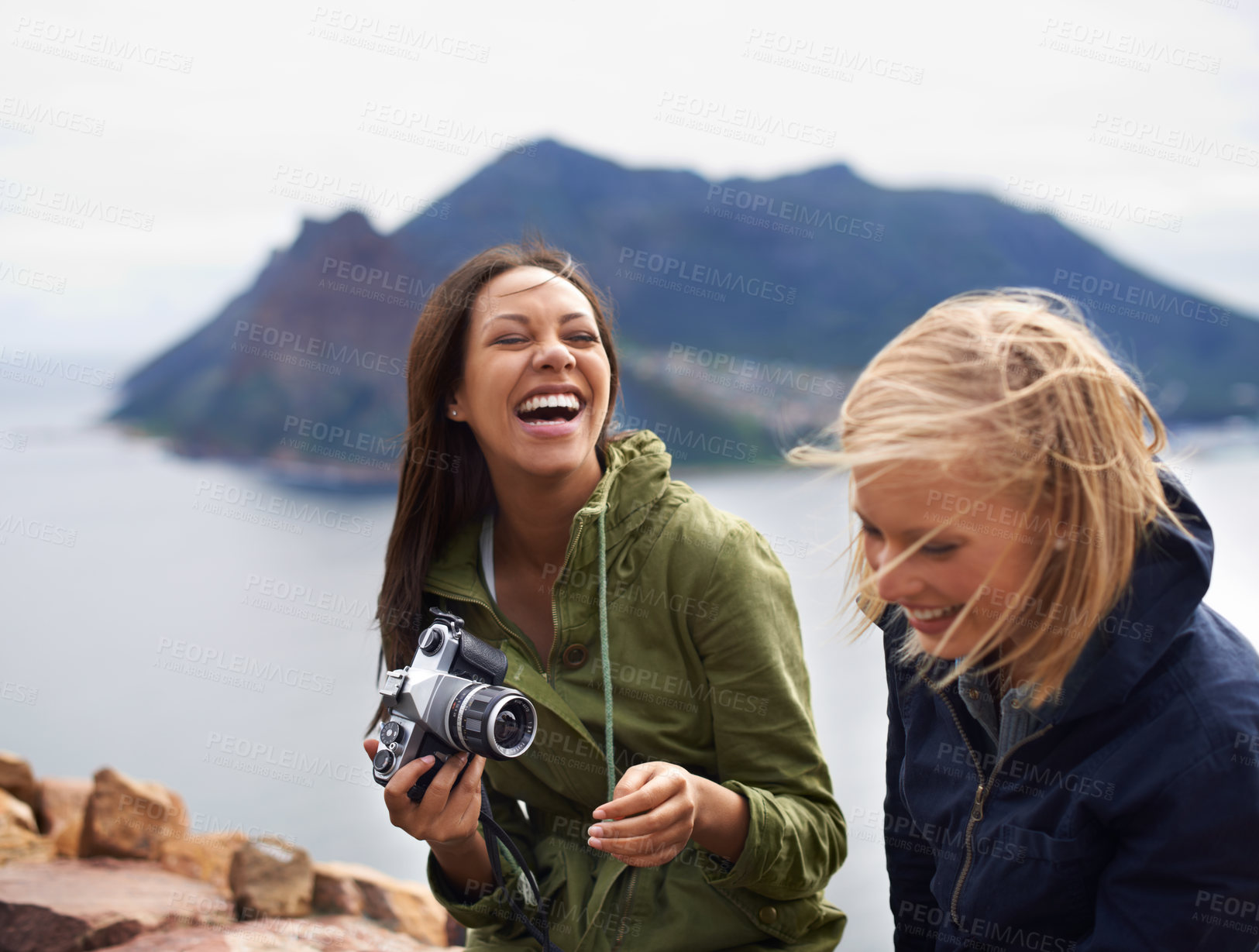 Buy stock photo A shot of two young women laughing on the side of the road during their trip