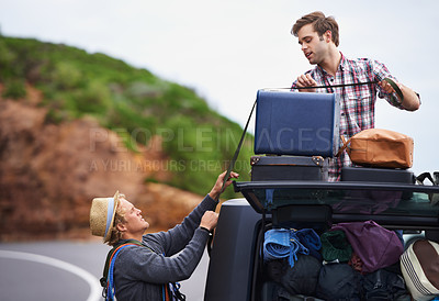 Buy stock photo Shot of two young men  stopped at the side of the road and repacking their truck