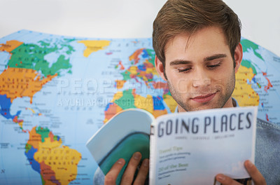 Buy stock photo Cropped shot of a young man reading a travel magazine