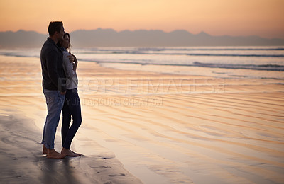Buy stock photo Silhouette of a young couple enjoying a romantic walk on the beach