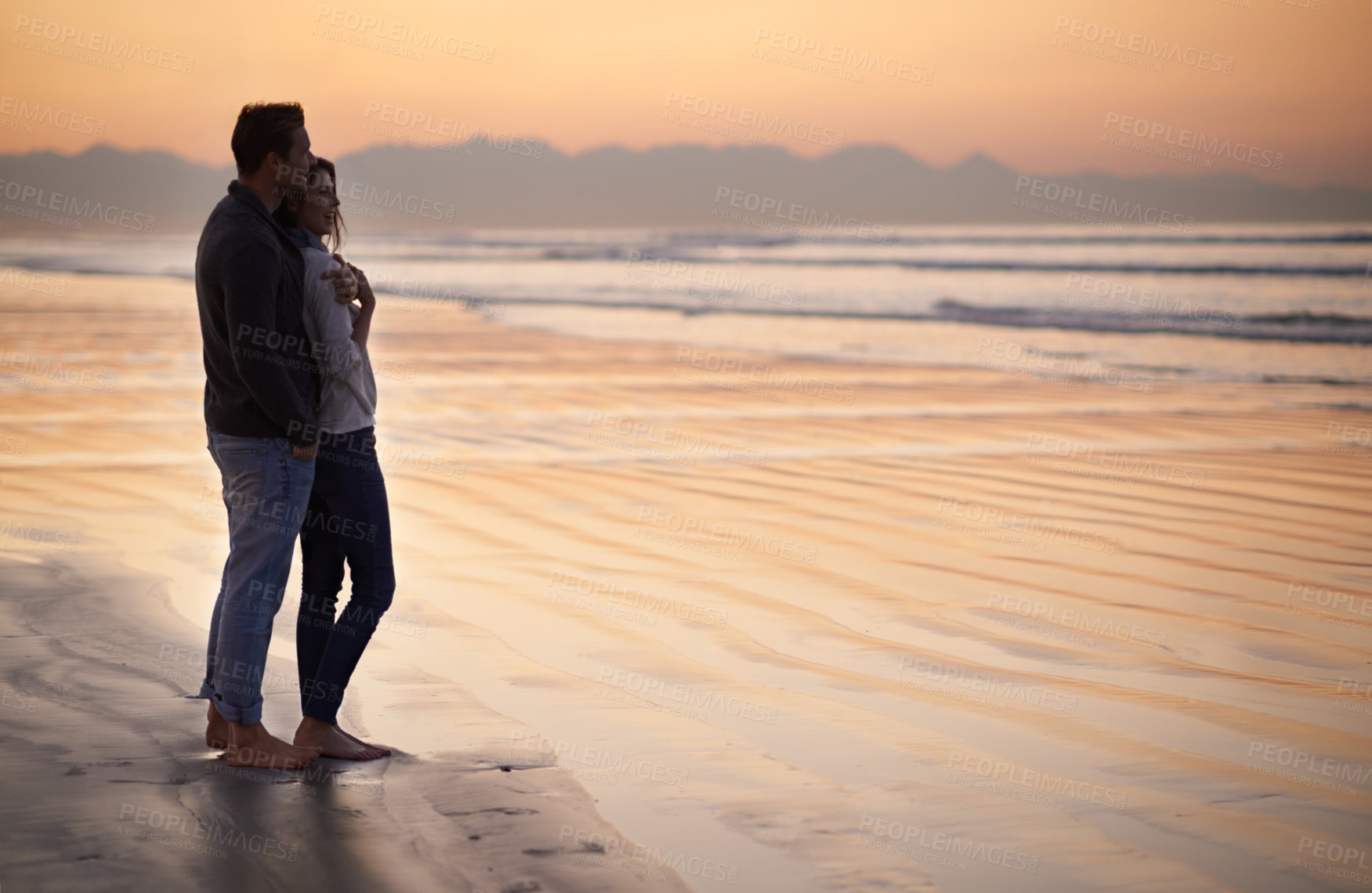 Buy stock photo Silhouette of a young couple enjoying a romantic walk on the beach